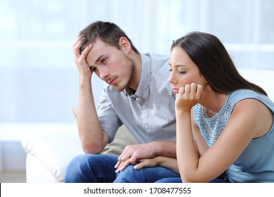 Sad Worried Couple Complaining Together Holding Hands On A Couch At Home