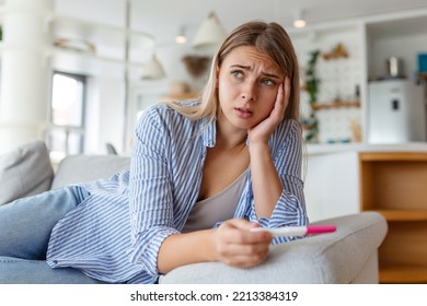 Sad, Worried Woman Checking Her Recent Pregnancy Test, Sitting On Couch At Home. Maternity, Child Birth And Family Problems Concept. Unwanted Pregnancy