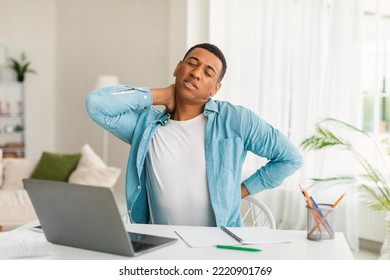 Sad Young African American Man Use Computer For Study, Work, Suffering From Fatigue And Back, Neck Pain In Room Office Interior. Health Problems, Business And Freelance Remotely At Home, Covid-19