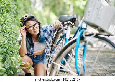 Sad Young Asian Woman In Helmet Checking Broken Bicyle Spoke