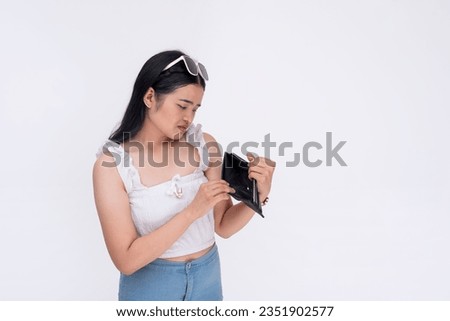 A sad young asian woman realizes her wallet is empty after checking its contents. A penniless and bankrupt lady in debt. Isolated on a white background.