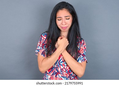 Sad young beautiful brunette woman wearing colourful dress over white wall desperate and depressed with tears on her eyes suffering pain and depression  in sadness facial expression and emotion .