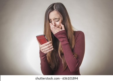 Sad young beautiful girl reading a message containing bad, terrible news
