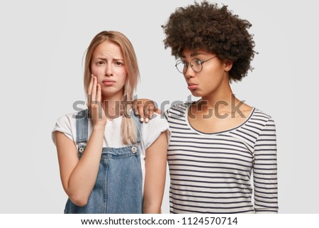 Sad young European female being calmed by her close African American woman friend, recieves words of support and help, has difficult situation in life, feel desperate after divorce with husband.