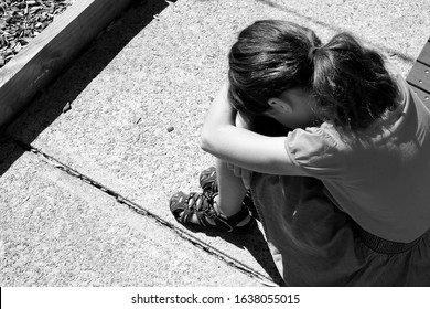 Sad Young Girl (female Age 9-10) Covering Her Face And Crying In School Yard. Child Bullying Concept. Real People. Copy Space