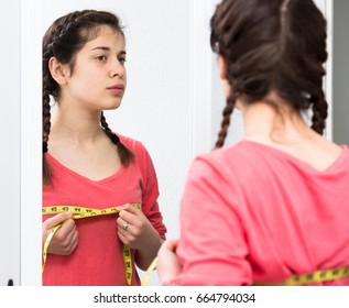Sad young girl measuring breast with precision at home - Shutterstock ID 664794034