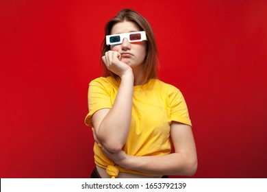 Sad Young Girl Watching A Bad, Boring Movie In 3d Glasses And With Popcorn On A Red Background, Copy Space