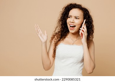 Sad young indignant woman bride wear white wedding dress posing talk speak on mobile cell phone argue isolated on plain pastel light beige background studio portrait Ceremony celebration party concept - Powered by Shutterstock