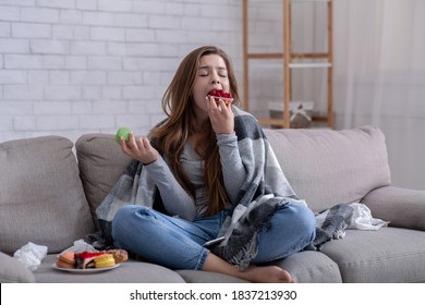 Sad young lady coping with depression or stress by eating sweets on sofa at home. Unhappy millennial woman dealing with stressful situation, loneliness or personal drama by comfort food