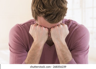 Sad young  man covering face with hands from desperation