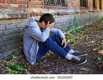 Sad Young Man near the Brick Wall of the Old House