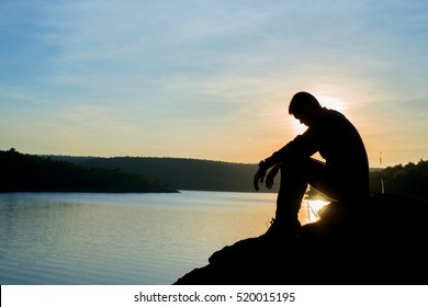 Sad Young Man Silhouette Worried On The Stone At Sunset ,Silhouette Concept