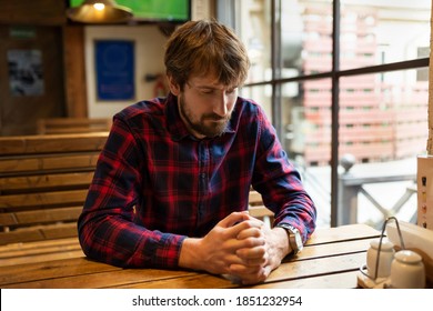 Sad Young Man Sitting Alone At A Table In A Bar. Alcohol Addiction Concept