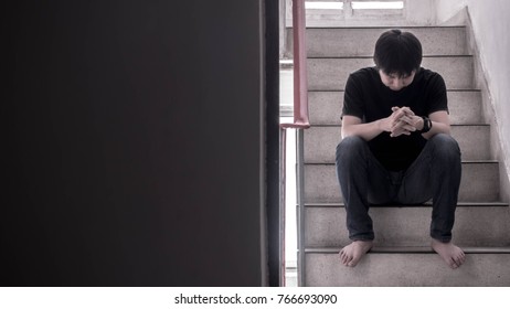 A Sad Young Man Sitting On The Stairs Fire Escape.