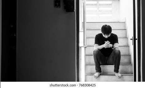 A Sad Young Man Sitting On The Stairs Fire Escape, With His Back