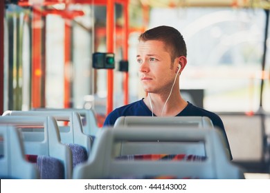 Sad young man is traveling by tram (bus). Everyday life and commuting to work by public transportation. Man is wearing headphones and listening to music. - Powered by Shutterstock