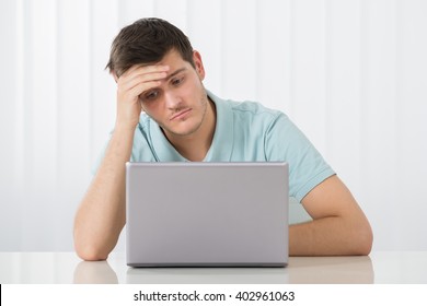 Sad Young Man Working On Laptop At Desk