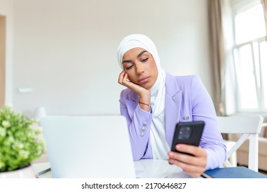 Sad Young Muslim Woman Using Mobile Phone And Laptop