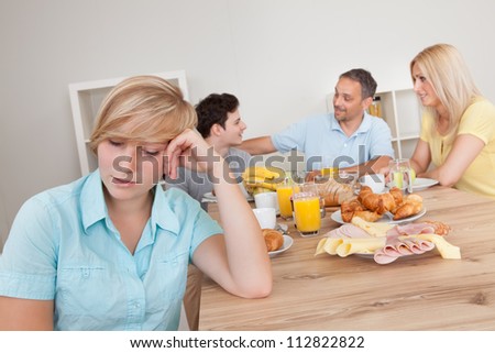 Sad young teenage girl sitting forlornly in the foreground