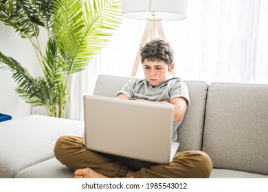 A Sad Young Teenager Using Laptop On Sofa At Home