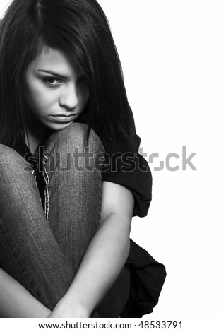 Sad young woman crouching on floor (acting)