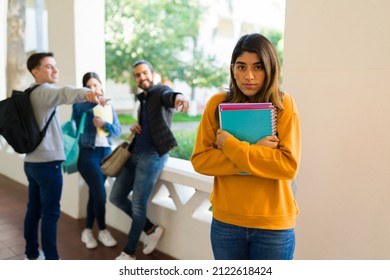 Sad young woman feeling depressed and ashamed while college students bully her on campus 