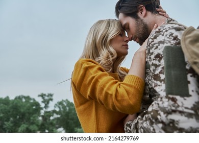 Sad young woman hugging and touching face of her husband before his leaving on war - Powered by Shutterstock