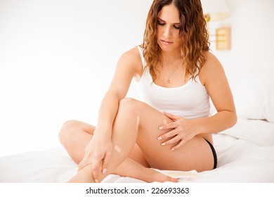 Sad Young Woman Looking At Her Cut Legs With Adhesive Bandages After Shaving Her Legs