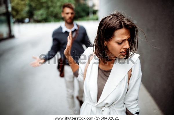 Sad young woman and man outdoor on street having\
relationship problems