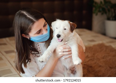 Sad Young Woman In Medical Mask With Dog Jack Russell Broken Stay Isolation At Home For Self Quarantine. Concept Home Quarantine, Prevention COVID-19, Coronavirus Outbreak Situation