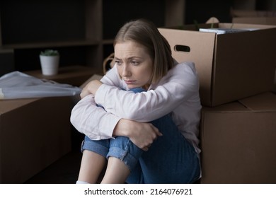 Sad young woman sits near heap of cardboard boxes with personal belongings looks upset goes through divorce, unsuccessful marriage and property division, move-out day. Eviction, mortgage debt concept - Shutterstock ID 2164076921