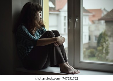 Sad Young Woman Sitting On The Window, Watching Out