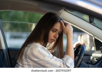 Sad young woman suffer from stress inside car. Upset unhappy female driver sit on front seat pensive think of breakup, problem at work or study. Girl with pain from migraine or headache drive vehicle