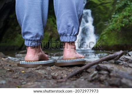 Sadhu boards in nature. Therapy of standing on nails in nature on the background of a waterfall