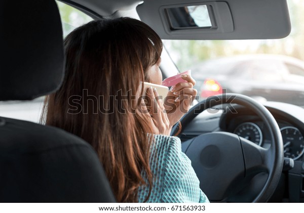 sadness, the driver was stuck in traffic. woman\
driver applying makeup using the rearview mirror in the car and\
talking on the phone while\
driving.