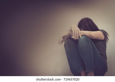 sadness young woman sitting on wood floor looking at empty dark area feeling unhappy and afraid on white wall background with battered abused woman concept.