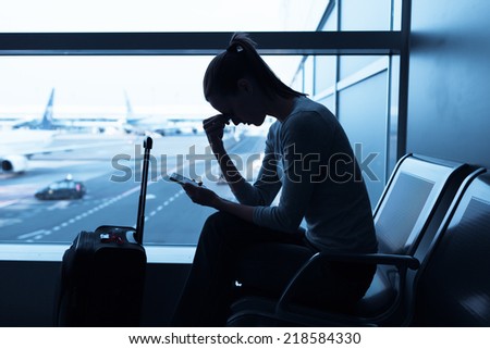 Sad/stressed/sick woman at the airport holding smart phone