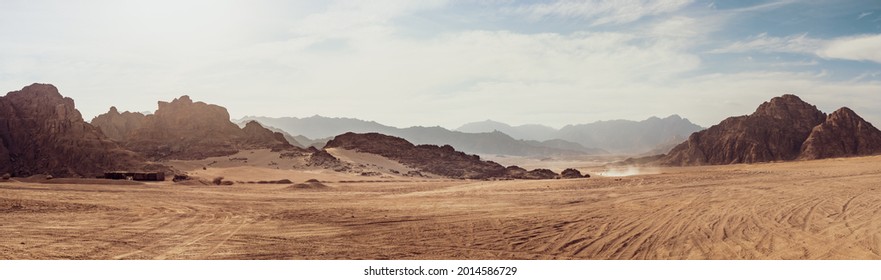 Safari and travel to Africa, extreme adventures or science expedition in a stone desert. Sahara desert at sunrise, mountain landscape with dust on skyline, hills and traces of the off-road car. - Powered by Shutterstock
