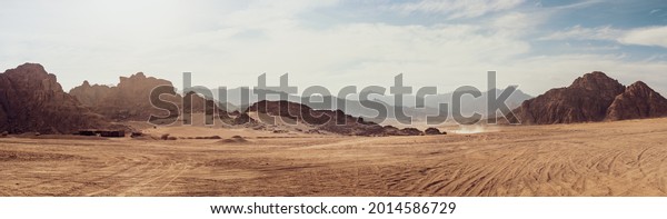 Safari and travel to Africa, extreme adventures or\
science expedition in a stone desert. Sahara desert at sunrise,\
mountain landscape with dust on skyline, hills and traces of the\
off-road car.