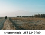 Safari vehicle - Amboseli National Park with a hazy view of  Mount Kilimanjaro, Kenya