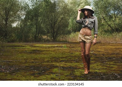 Safari Woman In Swamp Wearing Safari Hat Standing On Moss