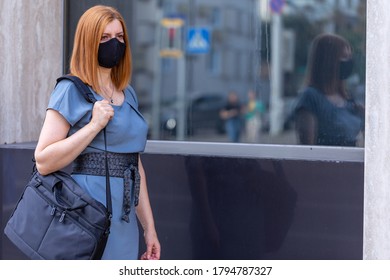 Safe Business Travel. Female In Black Mask With Laptop Bag Near The Office Glass Door. City View.