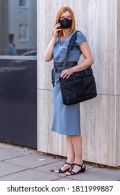 Safe Business Travel. Female In Black Mask With Laptop Bag Ans Cell Phone . City View.