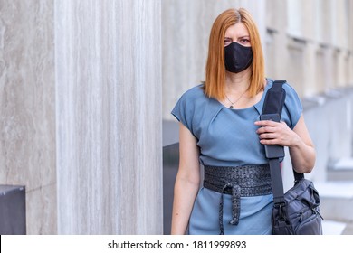 Safe Business Travel. Female In Black Mask With Laptop Bag Ans Cell Phone . City View.