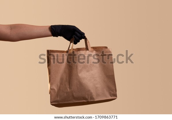 safe delivery for quarantine female hand in\
black latex glove gives paper\
bag