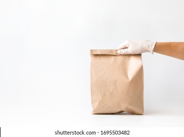 Сoncept of safe home delivery in a pandemic. Coronavirus 2019-nCov Protection. Courier  Paper bag hand in medical glove.Copy space . - Shutterstock ID 1695503482