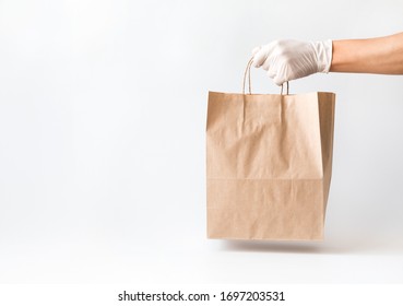 Сoncept of safe home delivery in a pandemic. Coronavirus 2019-nCov Protection. Courier  Paper bag hand in medical glove.Copy space . - Shutterstock ID 1697203531
