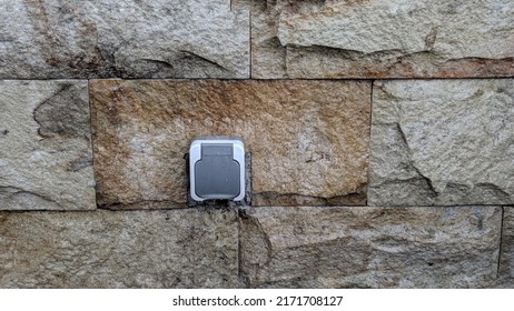 safe power socket installed on a stone wall. outdoor power outlet equipped with a plastic cover. waterproofed power plug