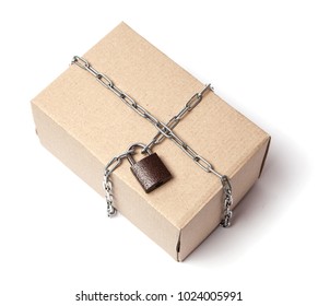 Safe Reliable Delivery Of Cargo In Safety Without Theft. The Cardboard Box Is Wrapped In A Chain With A Closed Lock. Isolated On White Background