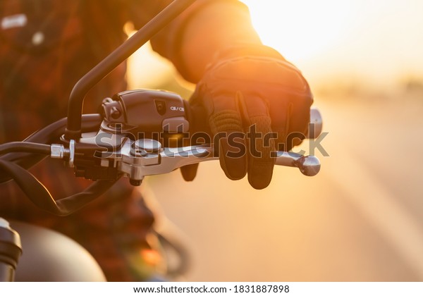 Safe ride concept. Macro left hand of motorcyclist\
wearing riding glove on the clutch. Outdoor shooting on the road\
with copy space